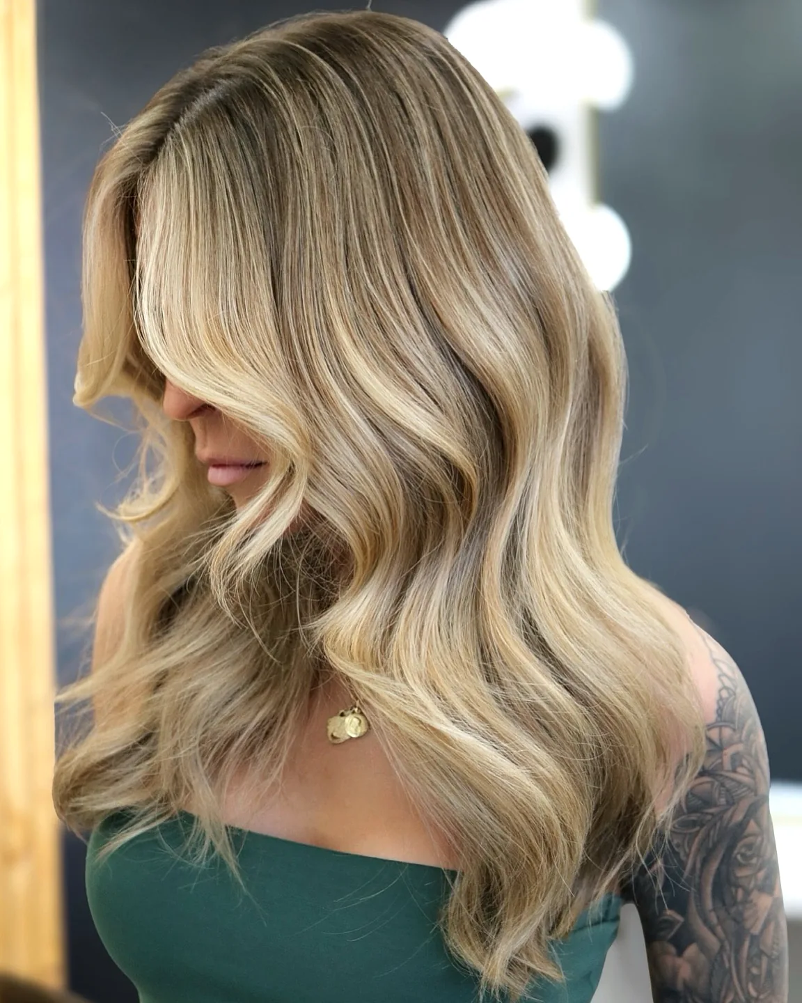 Dimensional blonde balayage with hand-painted highlights, styled in loose waves — hair color by Infinite Hair Studio, Baton Rouge LA